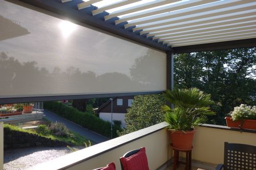 Teilweise verschattete Terrasse mit Markise, Balkonmöbeln und Pflanzen im Sommer.