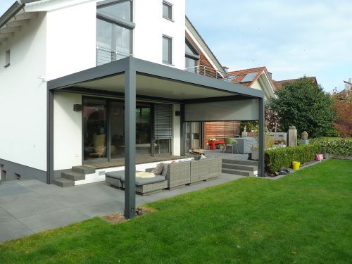 Moderne Terrasse mit Überdachung aus Aluminium und gemütlicher Gartensitzgruppe am Haus.