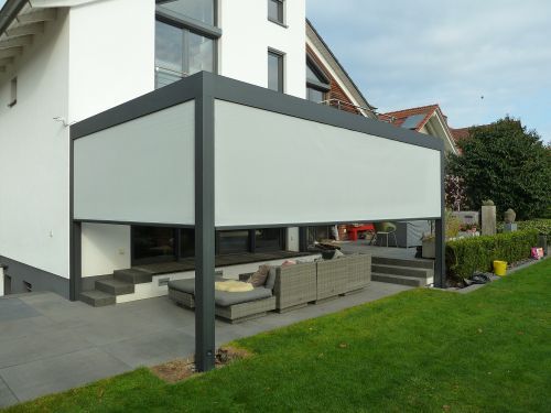 Moderne Terrassenüberdachung mit seitlichem Sonnenschutz an einem Einfamilienhaus.