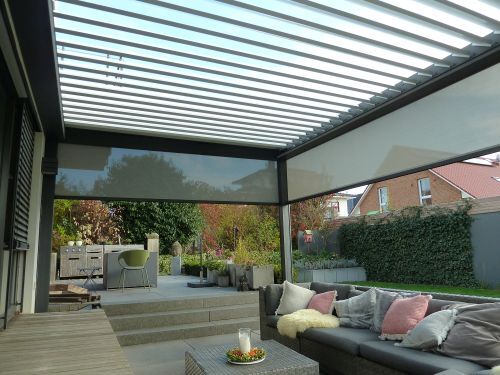 Moderne Terrasse mit Lamellendach, gemütlicher Sitzgruppe und Blick in den Garten.